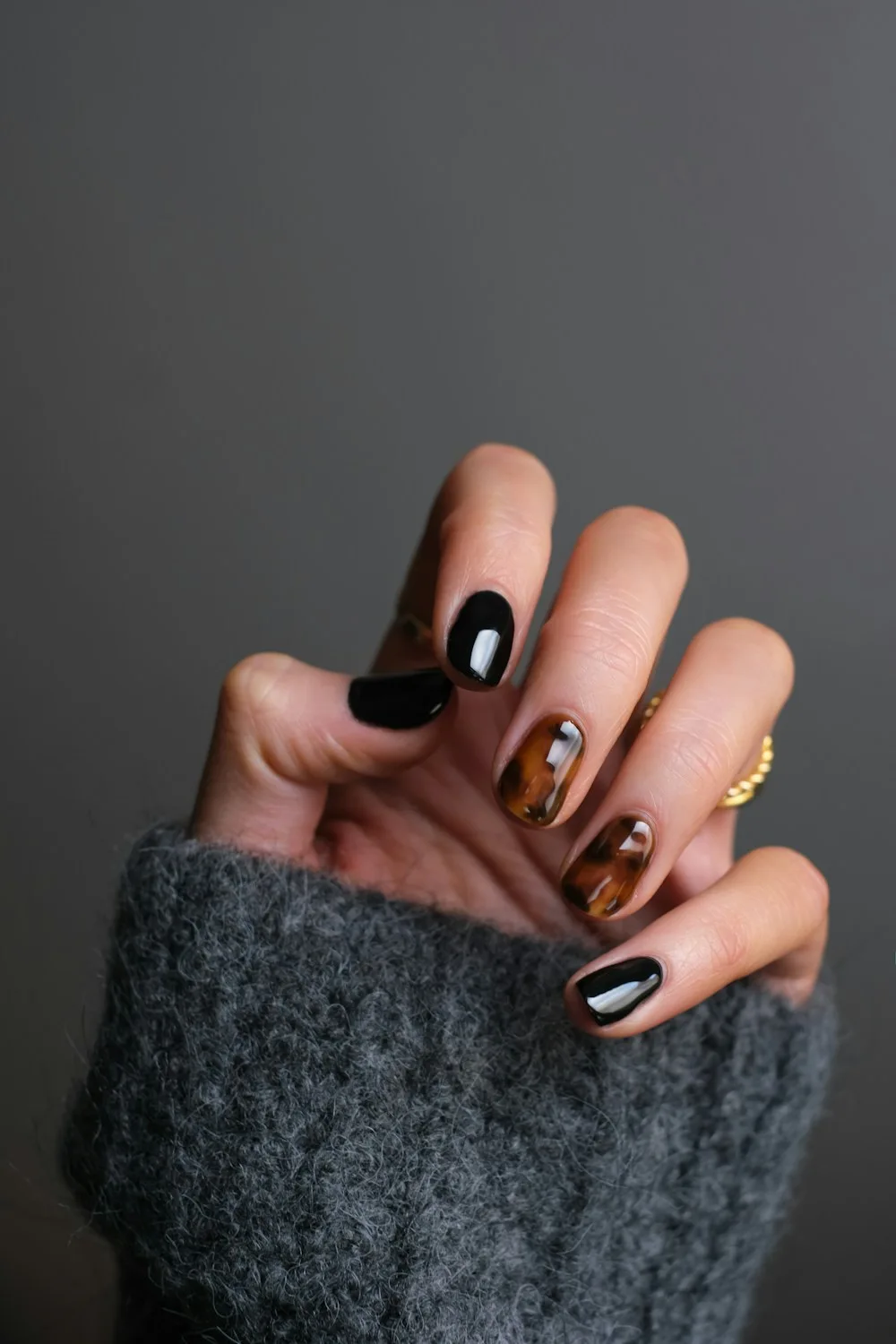 A glossy black manicure with tortoiseshell accent nails